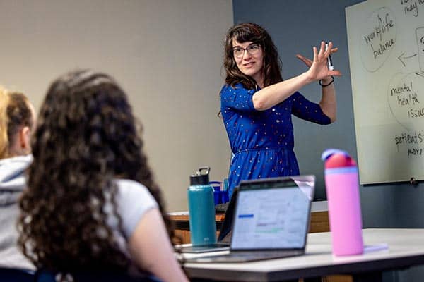 An instructor teaches students while standing in front of a classroom 