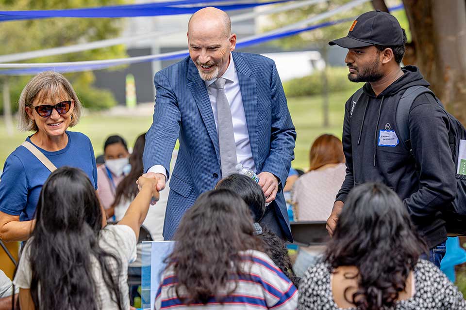 Ed shakes hands with an international student. 