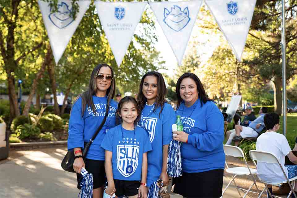 A family poses for a photo outside on campus.