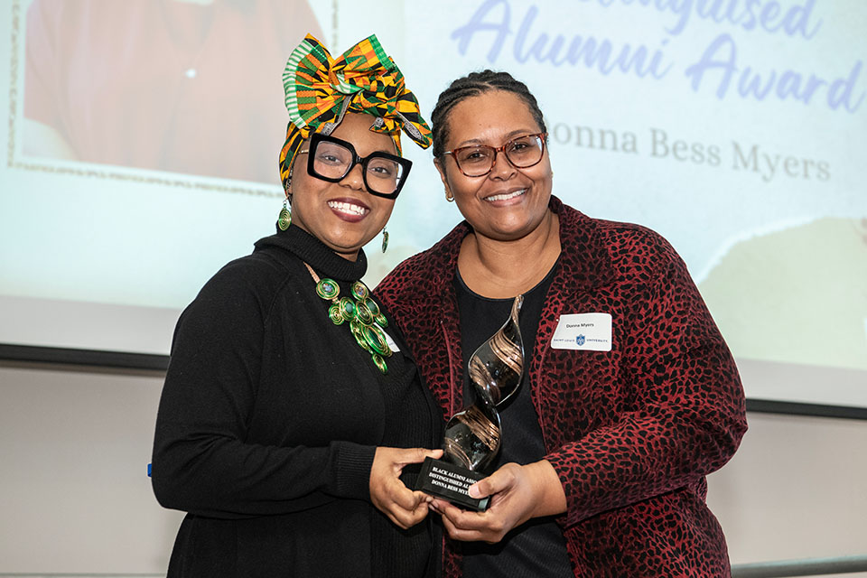 Two women pose for a photo holding an award.