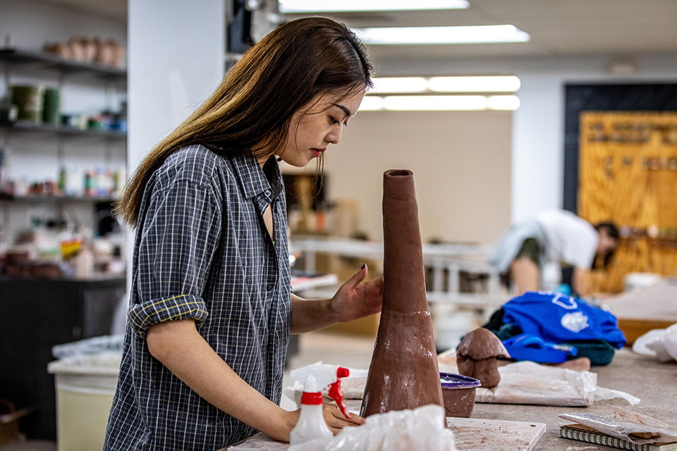 A student works on a ceramic artwork