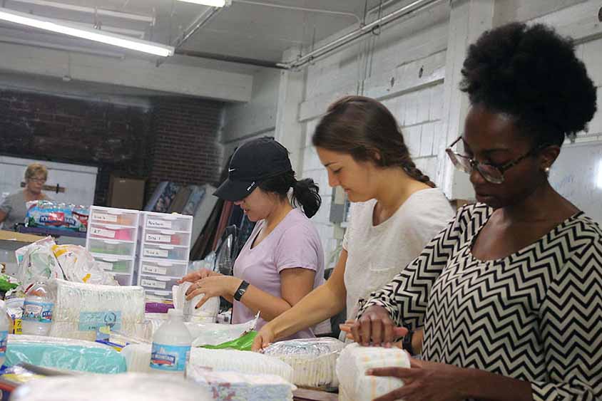 Students in work on a service project standing in a line at a counter