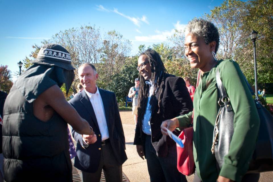 Three administrators and faculty shake hands with students.