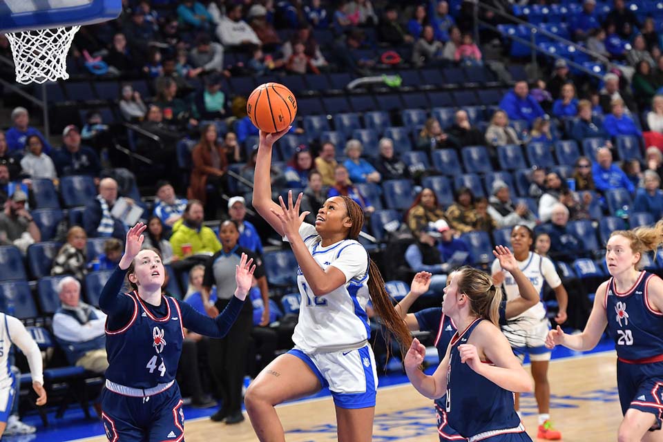 A women's basketball player shoots a basket.