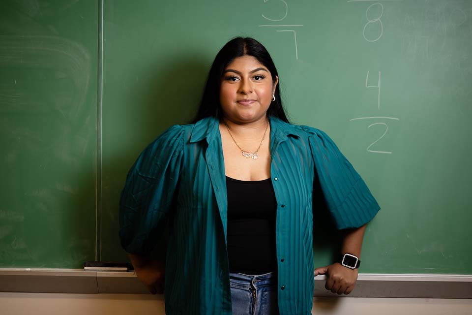 A student poses for a photo in front of a chalkboard