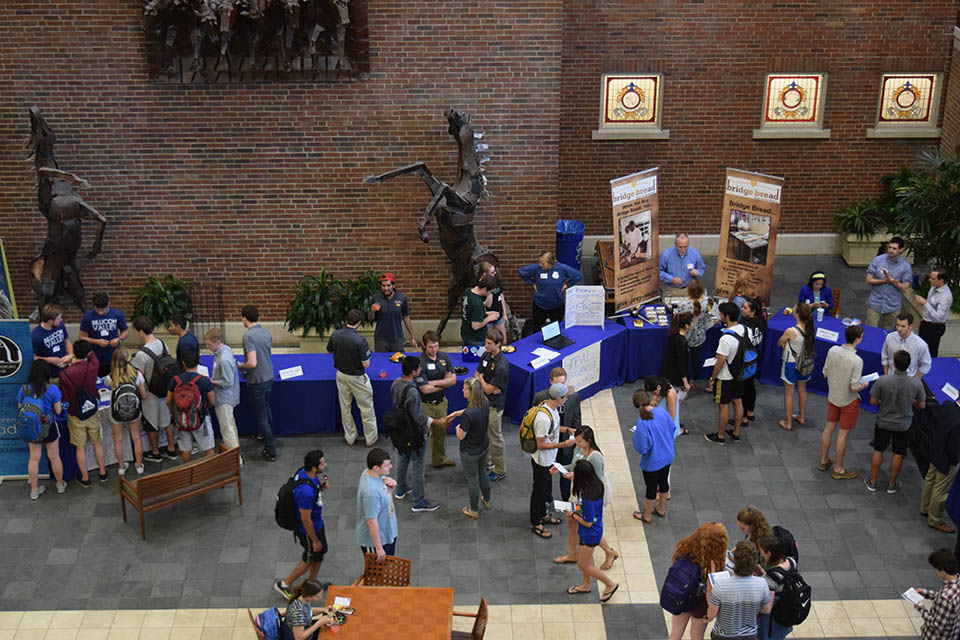 Students are shown from above as they mill about informational tables.