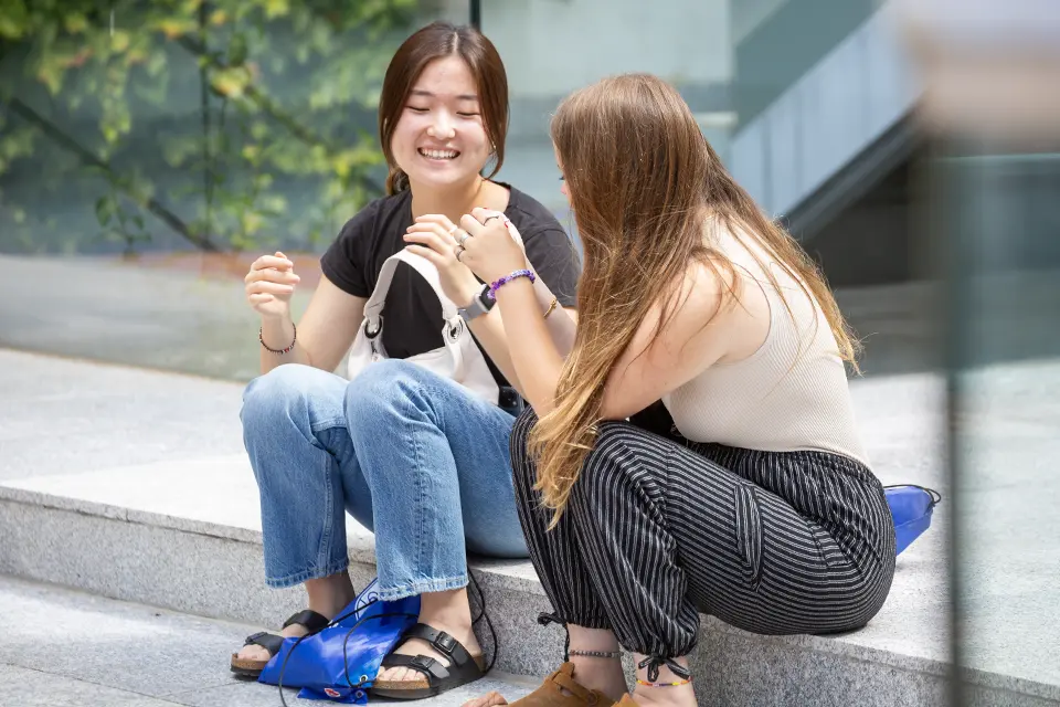 Two students talking while sitting at the PRH patio