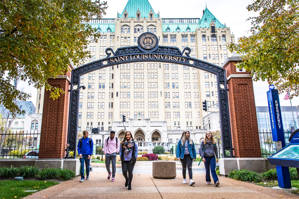 A group in front of the SLU sign on south grand