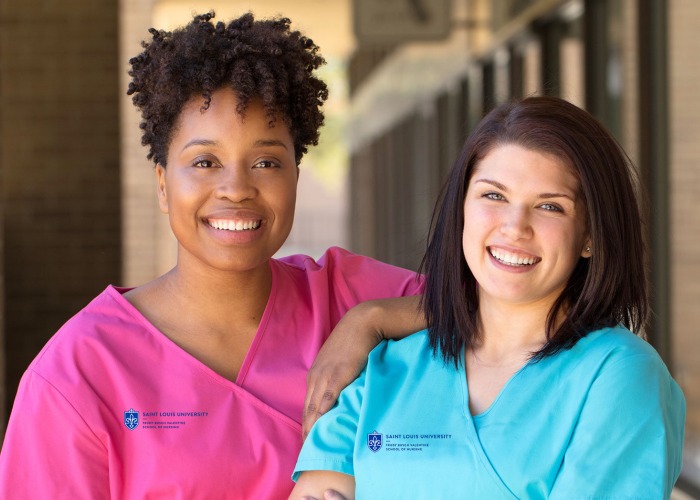 two SLU Nursing students in scrubs pose for a picture