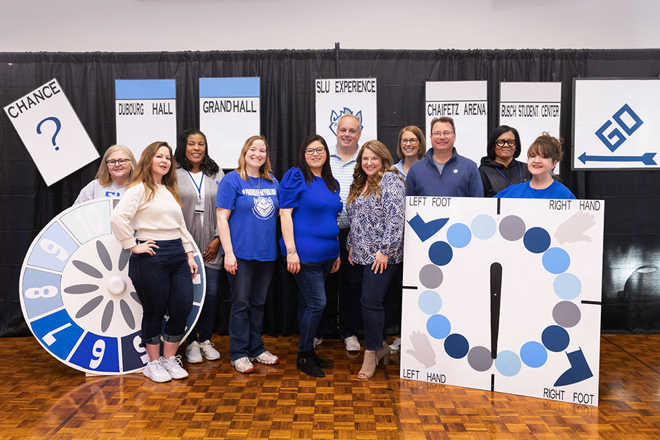 Eleven BPFA board members standing in front of board-game themed trivia night decorations.