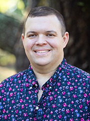 Smiling man in a colorful shirt in an outdoor setting